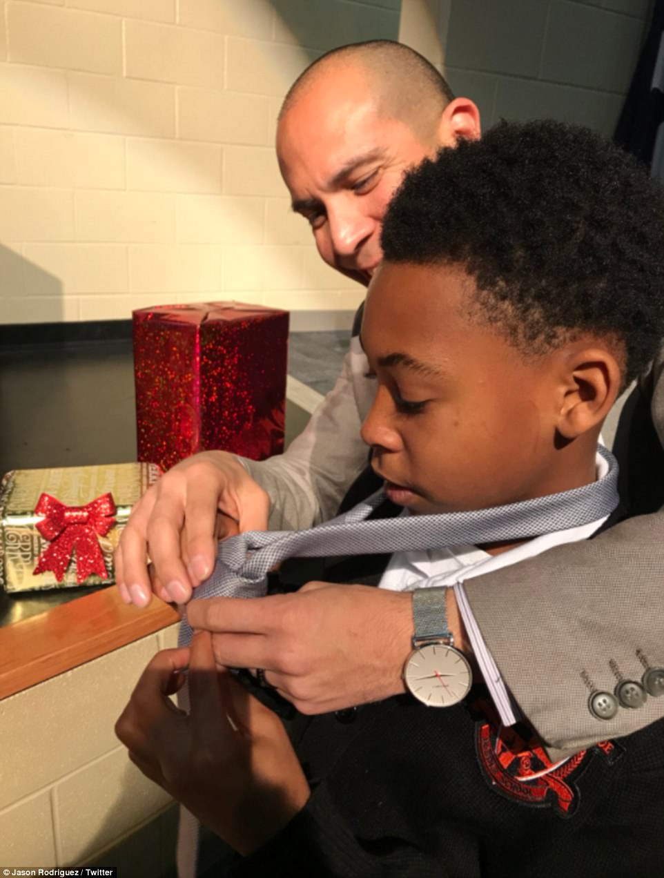 Rodriguez is seen showing one of the young boys how to tie a necktie