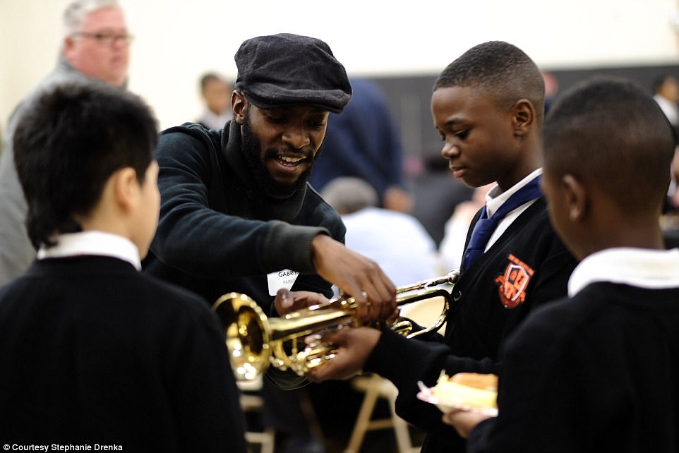 And on the day of the program, event organizers were overcome with emotion when 600 men showed up to support their students. This mentor is showing students how to play the trumpet 